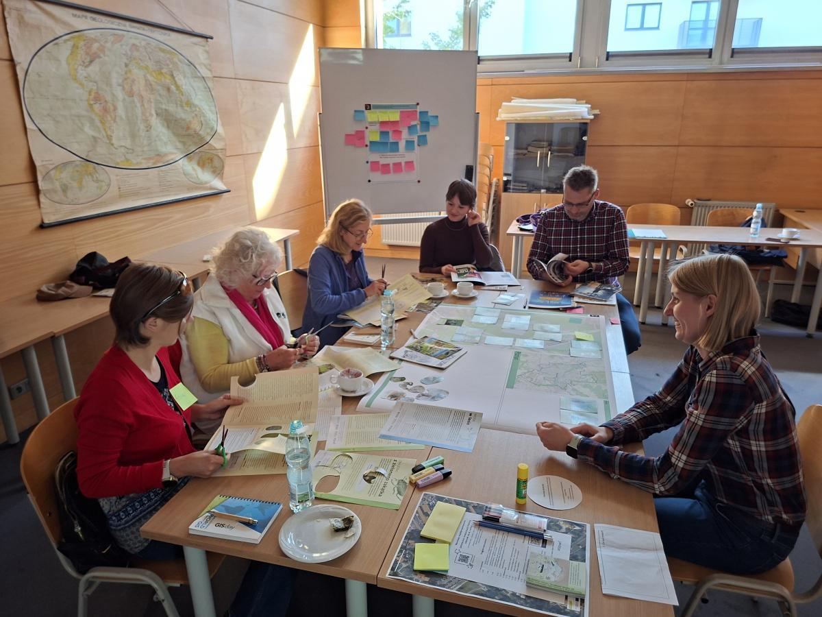 Uczestnicy warsztatów współprojektowania siedzą przy stole, analizując materiały dotyczące renaturyzacji Piaśnicy.